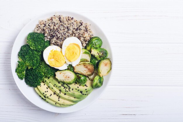 Buddha bowl with quinoa eggs avocado brussels sprouts and broccoli Food vegan salad on wooden backgground