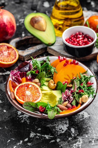 Buddha bowl with vegetable, fruits and seeds on a dark background. vertical image