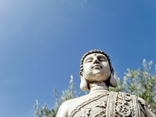 Busto di buddha in primo piano con il cielo sullo sfondo