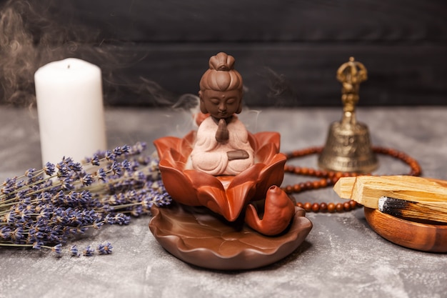 Buddha figurine and smoky incense with bell and rosary aromatherapy