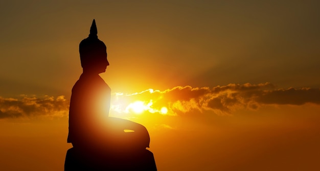 仏教の黄金の夕日の背景の信念に仏のシルエット