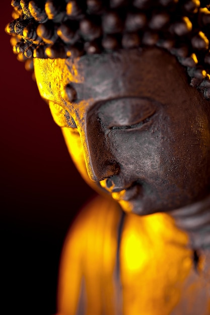 Buddha statue head with glow against black background