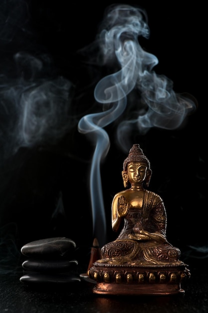 Buddha statue incense sticks and black zen stones