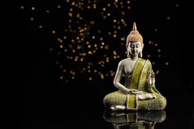 Buddha statue in meditation with lights on black background\
with copy space