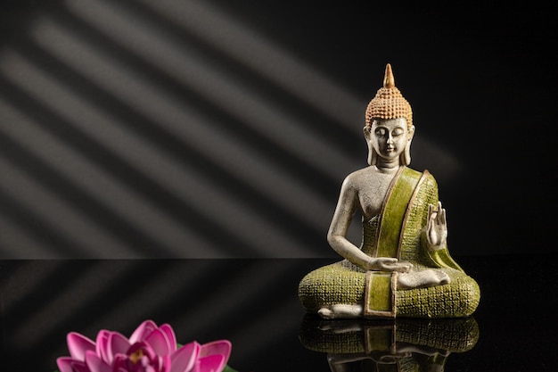 Buddha statue in meditation with shadows on dark background with copy space