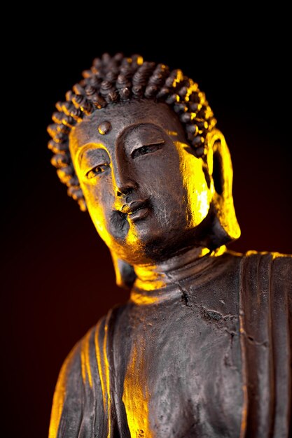 Buddha statue with glow against black background