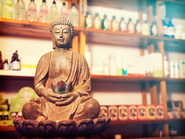 Buddhist monk statuette in front of exhibitor with natural products for sale