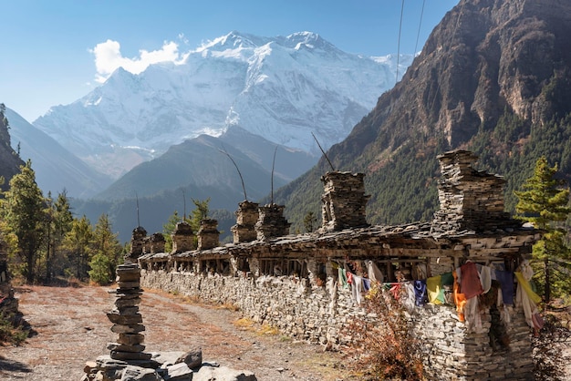 배경 안나푸르나 서킷 트렉 히말라야 네팔 아시아(Annapurna Circuit Trek Himalaya 네팔 아시아)에 있는 안나푸르나 II 산 정상의 북벽이 있는 불교 기도 벽 또는 마니 벽