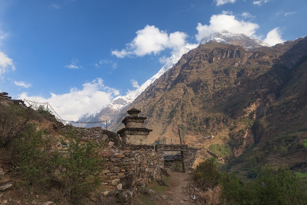 Buddhist stupa and stone gate on a pathway in a himalayn deep valley