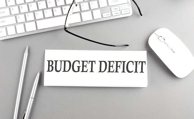 BUDGET DEFICIT text on paper with keyboard on grey background