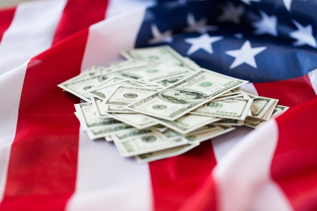 budget, finance and nationalism concept - close up of american flag and dollar cash money