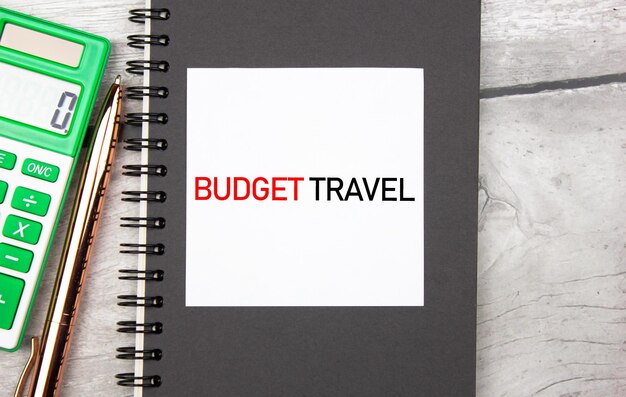 Текстовая концепция BUDGET TRAVEL в блокноте рядом с калькулятором Budget Travel дешевый недорогой туристический туризм