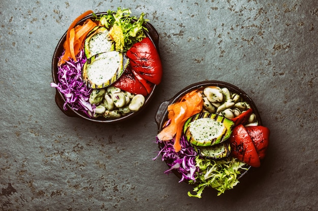 Budha bowl. Raw vegetables with beans, grilled avocado and bell pepper on slate background. Top view