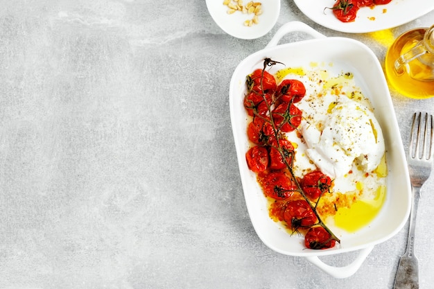 Photo buffalo mozzarela with roasted tomatoes and olive oil on plate. view from above.