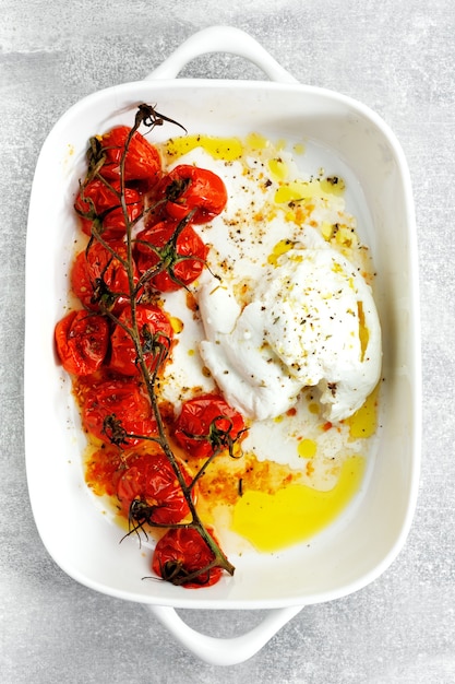 Buffalo mozzarela with roasted tomatoes and olive oil on plate. View from above.