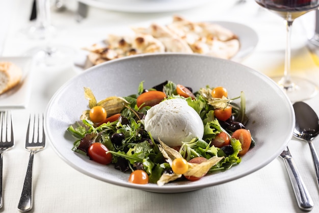 Buffelsalade met groene tomaten, physalis-olijven en de mozzarella als middelpunt