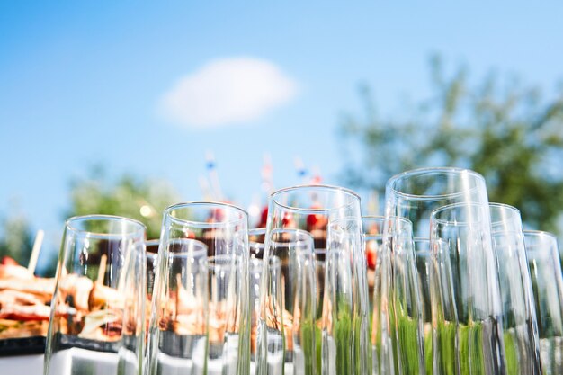 Buffet in the open air  empty glasses on the background of cold snacks against the sky