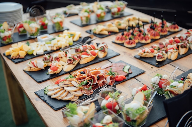 Foto tavolo buffet del ricevimento con hamburger, snack freddi, carne e insalate