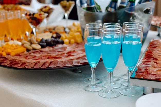 A buffet table with blue drinks and a tray of food with blue liquid.