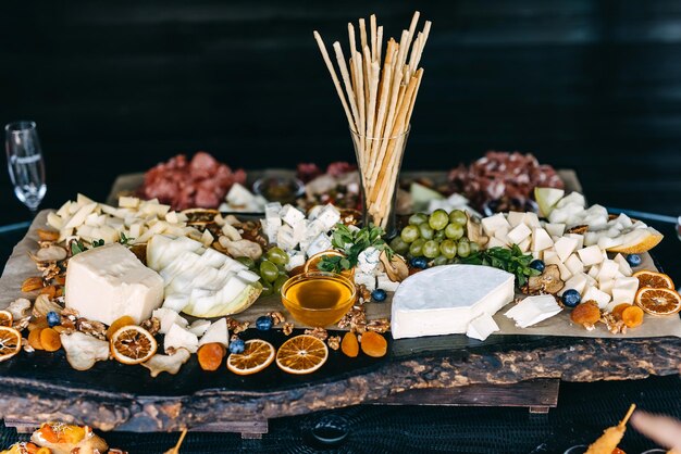 Photo buffet table with different cheese honey grapes and bread sticks at a party