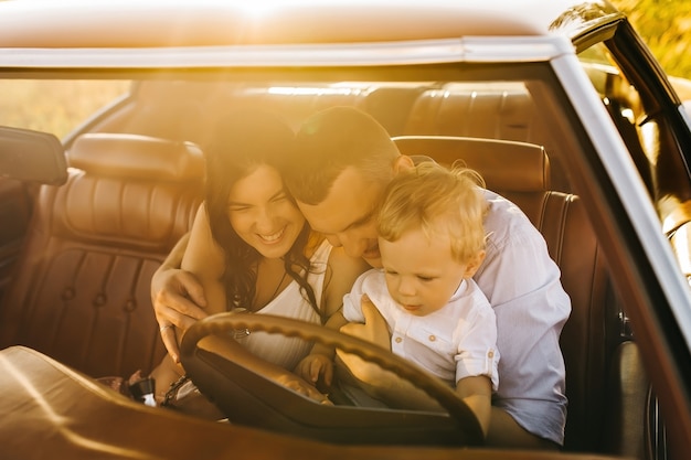 Buick Rivierin retro stijl. Unieke auto. Schattige blonde jongen zit achter het stuur van retro auto met zijn familie