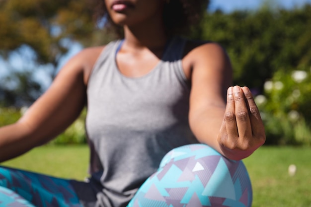 Buik van Afro-Amerikaanse vrouw die yoga beoefent in zonnige tuin. actieve levensstijl, outdoor fitness en vrije tijd.