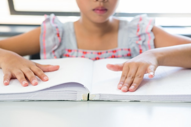 Buik van blind meisje die braille-boek lezen