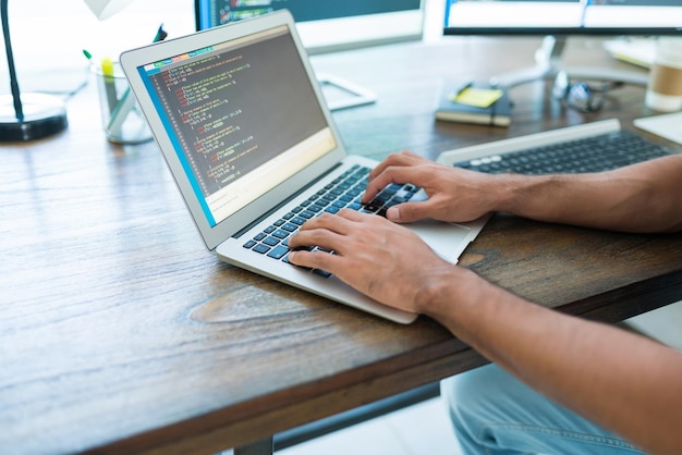 Buik van het coderen van professionele programmeersoftware op laptop aan bureau