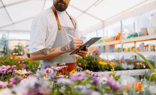 Buik van tuinman met tablet in tuincentrum foto van hoge kwaliteit