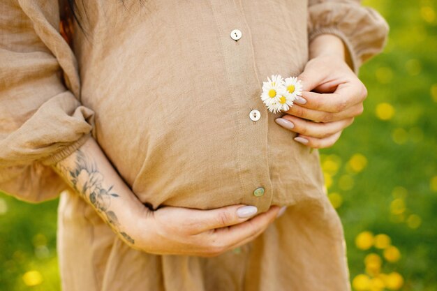 Buik van zwangere vrouw in een park met bloemen