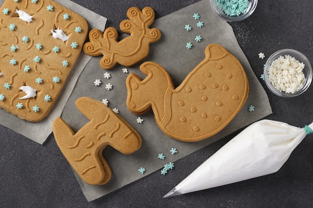 Build deer-shaped gingerbread at home. Step by step. Top view on dark gray background