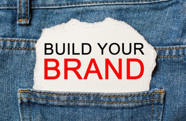 Build your brand on torn paper background on jeans business and\
finance concept