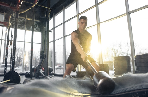 Создайте себя Молодой мускулистый кавказский спортсмен тренируется в тренажерном зале, делая силовые упражнения