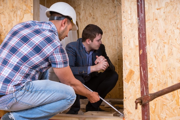 Builder and Architect Working Together and Inspecting Measurement of New Home Doorway Inside Building Construction Site, Ensuring Accuracy and Quality