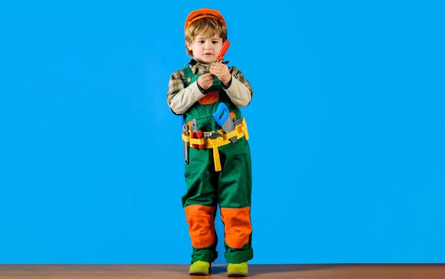 Builder boy in safety helmet and toolbelt with screwdriver child in uniform and hardhat with tool