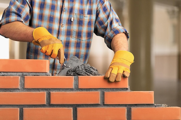 Builder carefully puts red brick on the masonry. Quick work bricklayer.