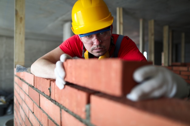 Photo builder carefully puts red brick on the masonry