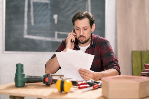 Builder checking through is notes over the phone