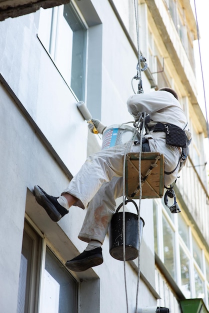 Builder climber paints the facade of the building