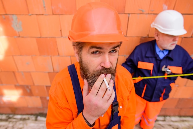 ハンサムなひげを生やしたエンジニアのタバコの肖像画を喫煙ビルダー男建設労働者はによってリラックスします