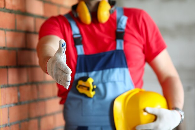 Builder at object holds out his hand for greeting.