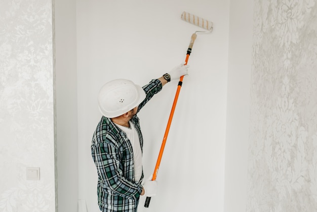 Photo builder painting the wall with a roller