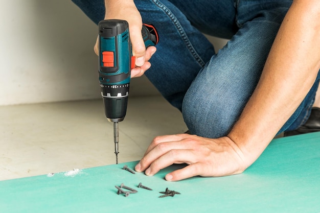 Builder spins the screw into a sheet of drywall Construction and repair concept