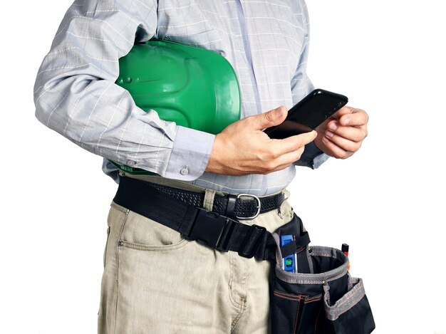 Builder with tools and hard hat holds smartphone in his hands