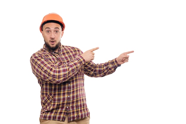 Builder worker in protective construction orange helmet hands pointing to the right, isolated on white background. Copy space for text. Time to work.