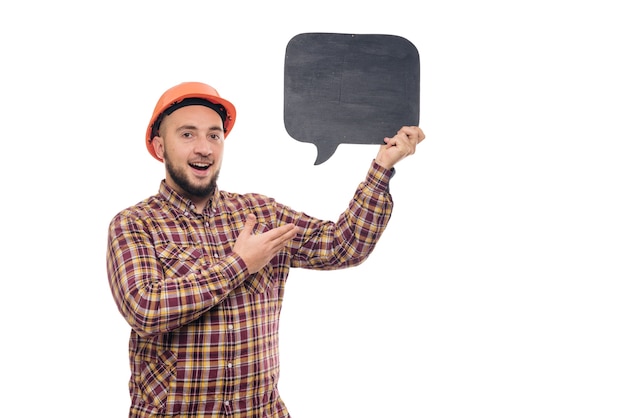 Builder worker in protective construction orange helmet holding black chalk board with space for informational tex, isolated on white background.