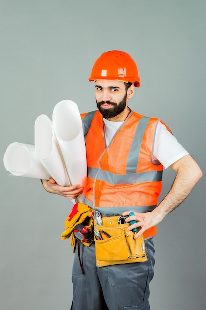 Builder or worker in a protective helmet with drawings in his hands Isolated on grey background