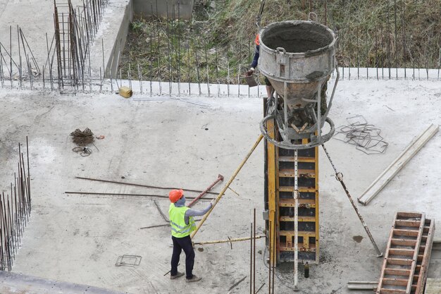 Builder worker with tube from truck mounted concrete pump pouring cement into formwork reinforcement