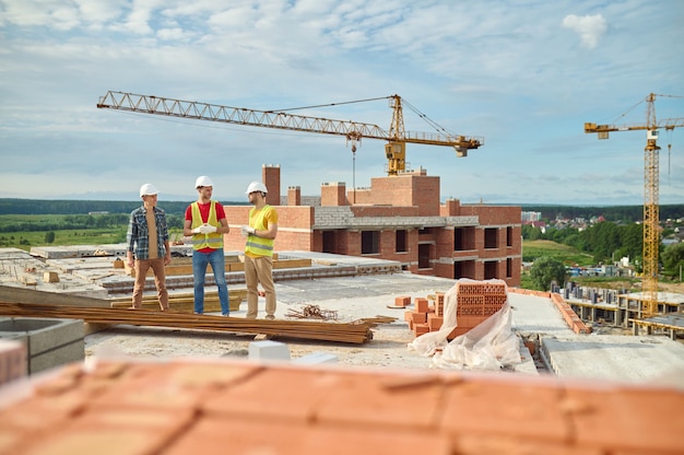 Builders in hardhats conversing with an engineer on the construction site