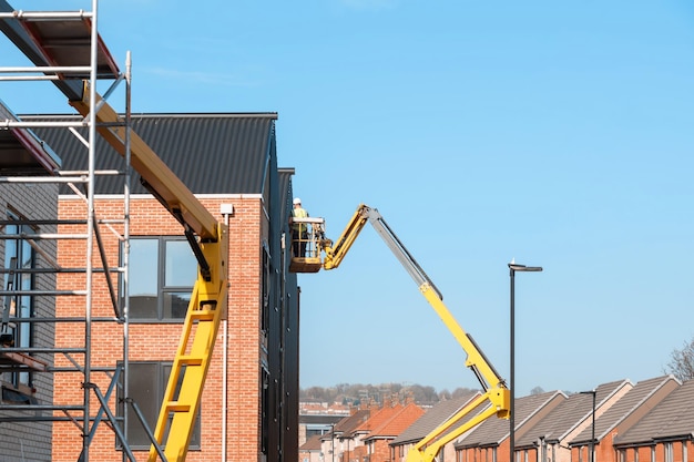 Builders working off telescopic boom lift while fitting\
insulated sandwich panels